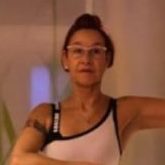 Frau in sportlicher Kleidung zeigt eine Pose, mit Brille und hochgestecktem Haar.